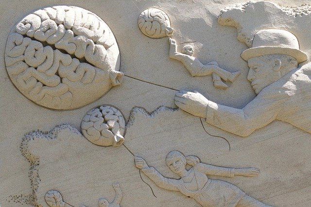 Escultura de areia mostrando pessoas voando com balões simbolizando cérebros e mente